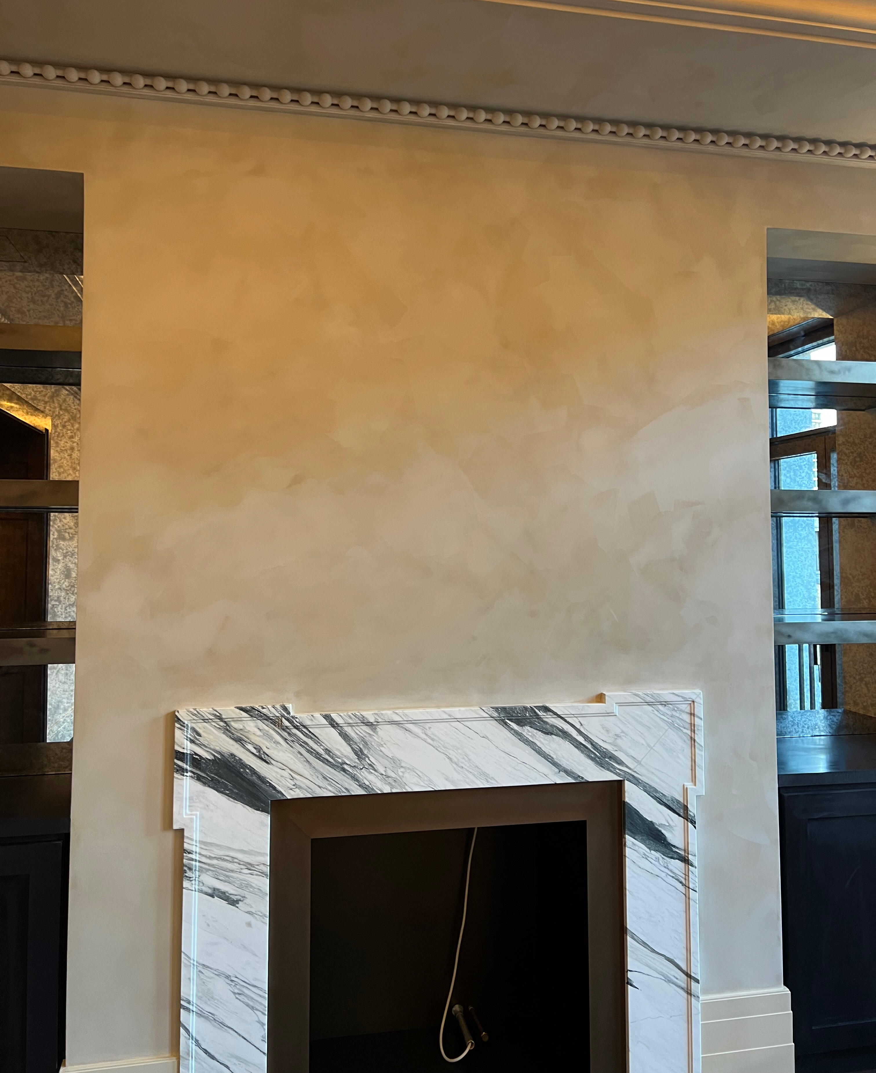 Warm cream limewashed chimney breast above a marble fireplace surround